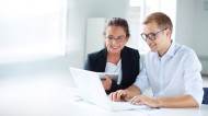 Two office workers looking at a laptop