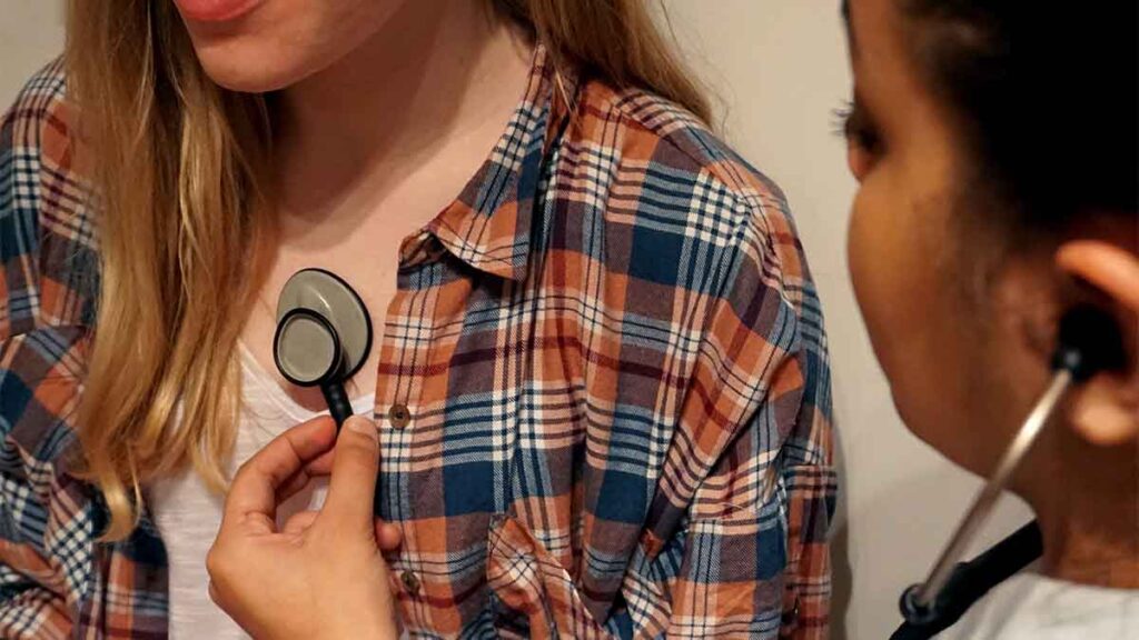 A doctor using a stethoscope on a female patient