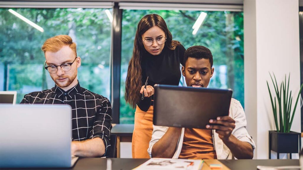 A group of younger workers using laptops and tablets in an office