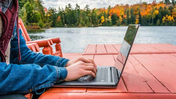 Working from anywhere webinar: man at a laptop by an autumnal lake.