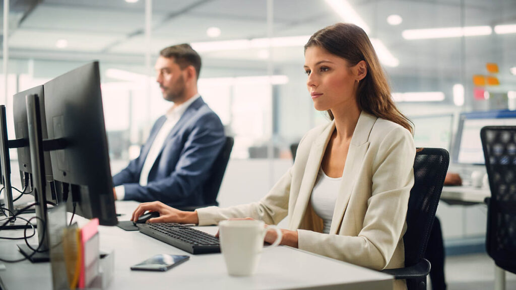 A woman and a man working at computers in an open plan office
