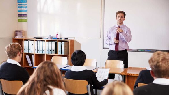 A teacher at the front of a classroom full of pupils