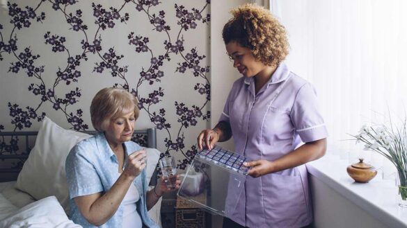 A female social care nurse sorting tablets for an elderly woman