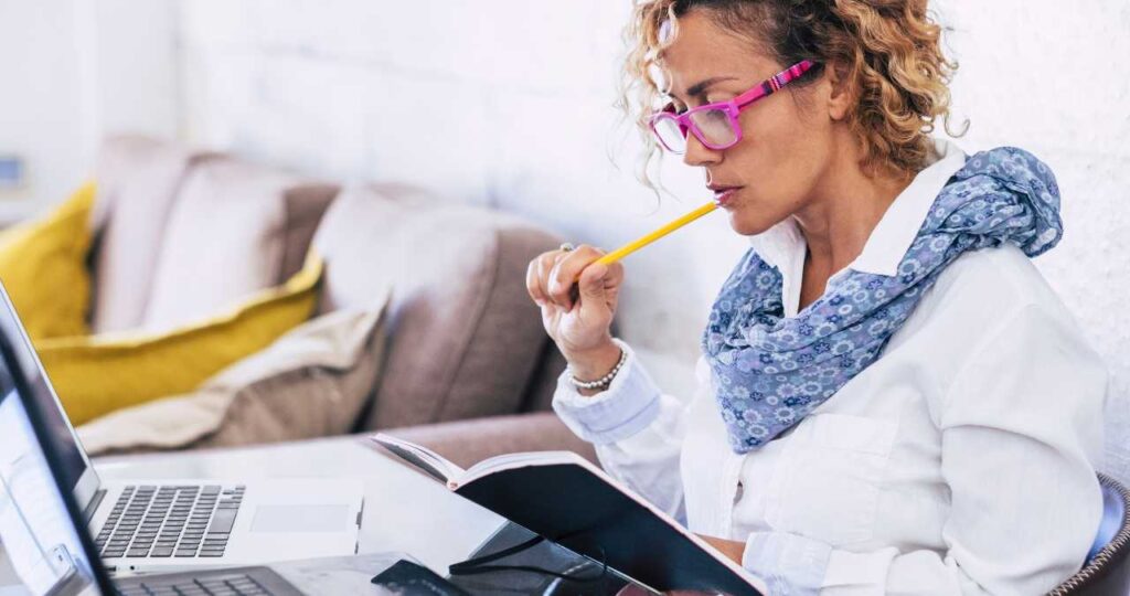 A woman studying at a computer, making notes