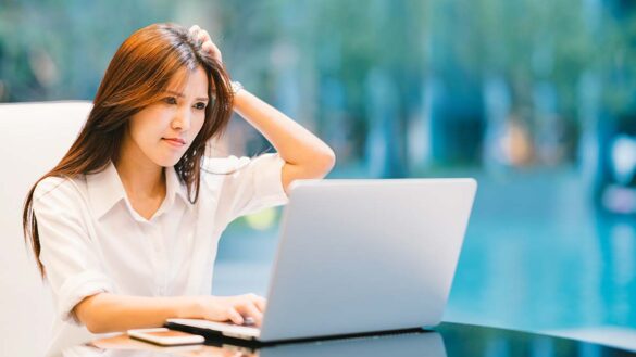 Irregular hours workers holiday pay: a woman scratching her head in confusion while sitting at a desk with a laptop