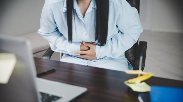 A woman with stomach cramps and period pain at work