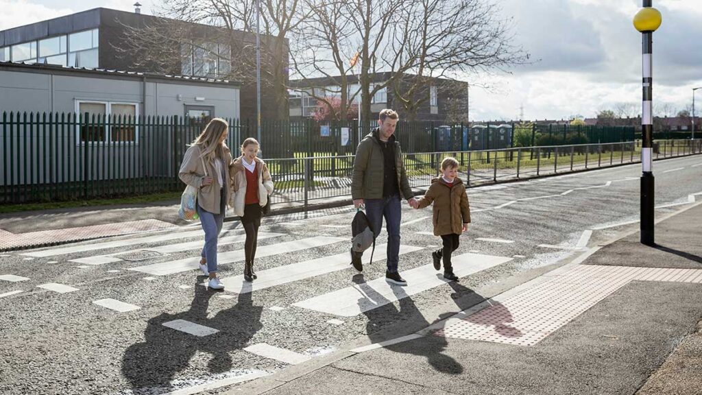 Parents taking children to school, walking across a zebra crossing