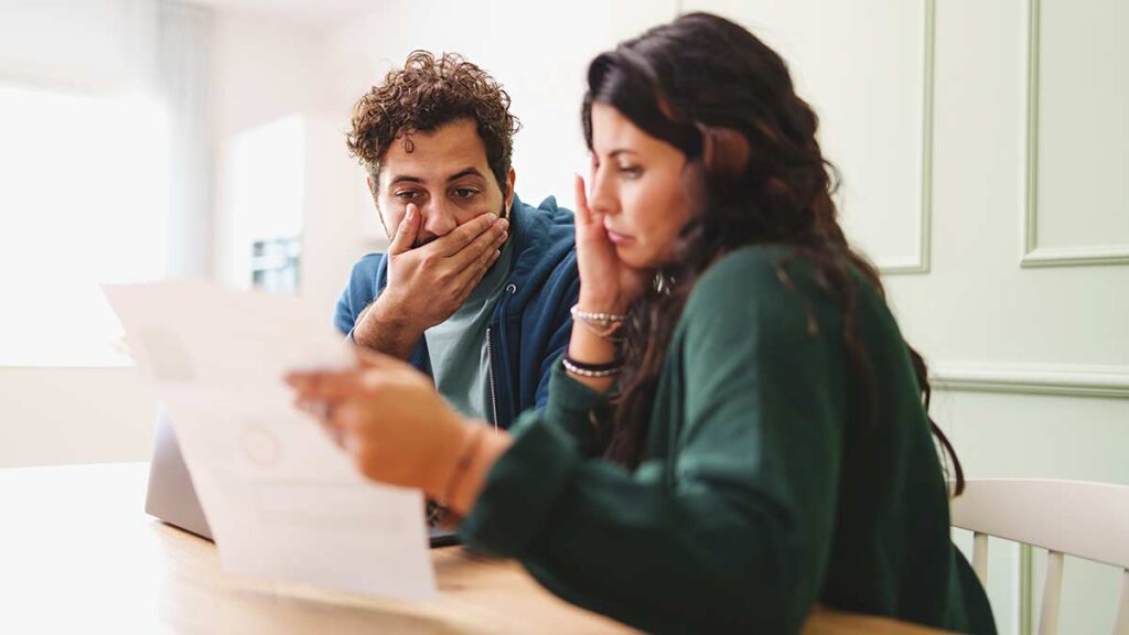 A worried couple looking at a bill
