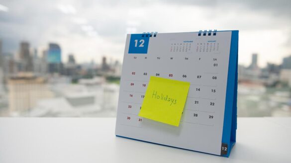 A sticky note with the word 'holiday' written on it, stuck to a calendar
