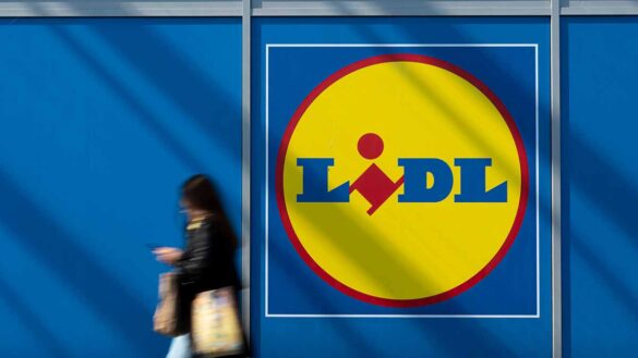 A woman walking past a Lidl supermarket