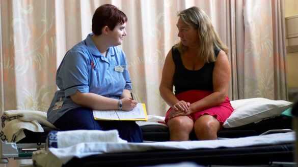 Nurse talking to a patient on a ward