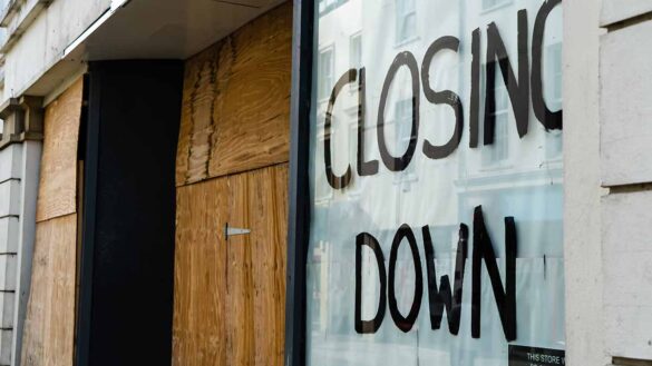 A boarded-up shopfront with 'closing down' painted on a window