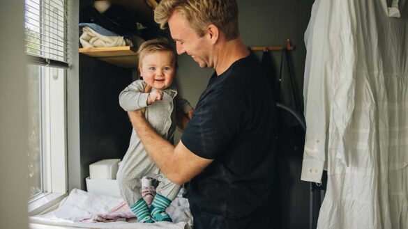 A father holding a baby on a changing mat