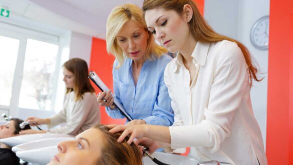 A hairdressing apprentice washing a client's hair in a salon, while being supervised