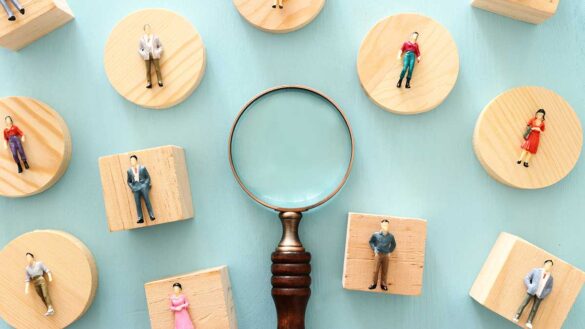 A magnifying glass and figurines on wooden blocks