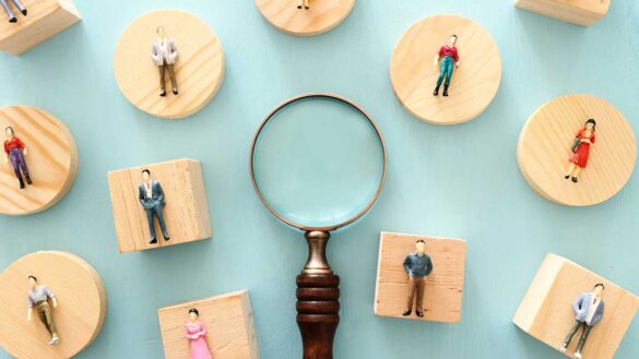 A magnifying glass and figurines on wooden blocks
