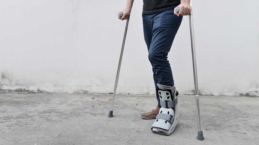 A man on crutches, with his left foot in an air boot