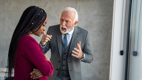 An older white man shouting at a younger black woman