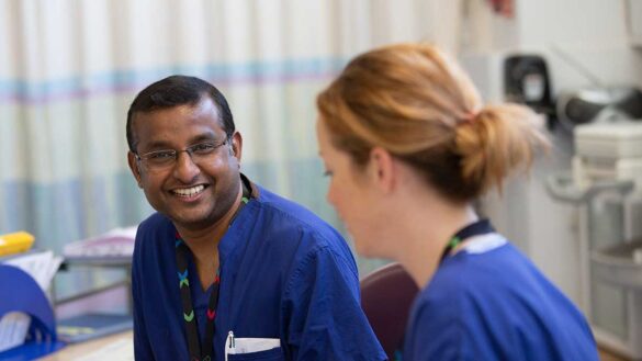 Two nurses talking at a workstation on an NHS ward