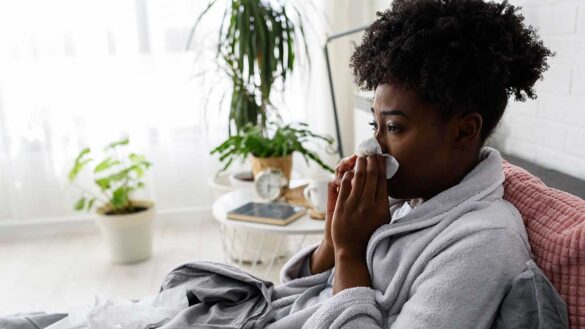 A woman off sick from work. Blowing her nose in bed.