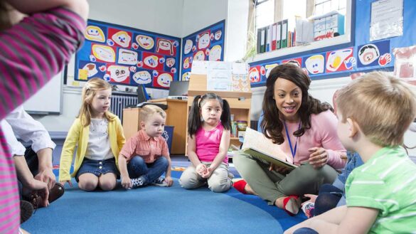 A childcare professional reading to children in a nursery