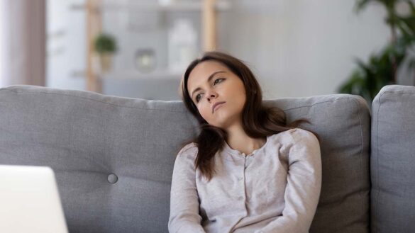 A bored woman sitting on a sofa at home