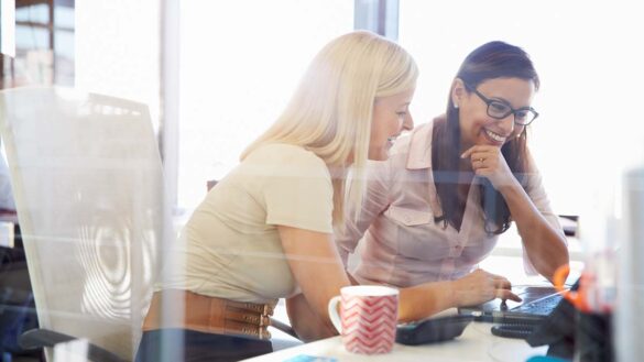 Two women working together at a laptop in an office