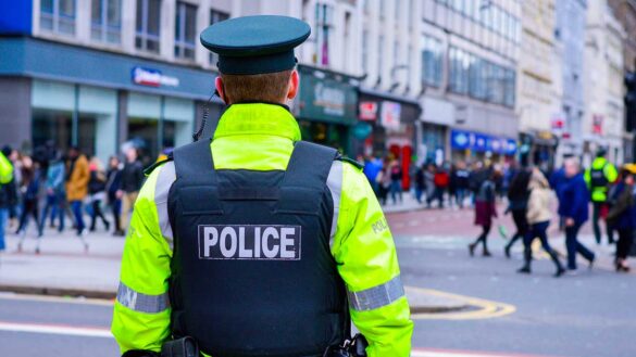 A police officer watching people walking on a busy high street