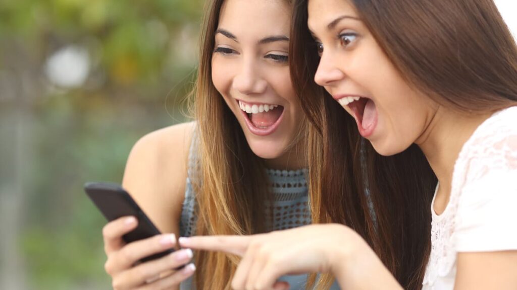 girls laugh at something on phone
