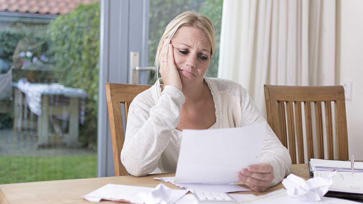 Woman looking at bills on a dining room table