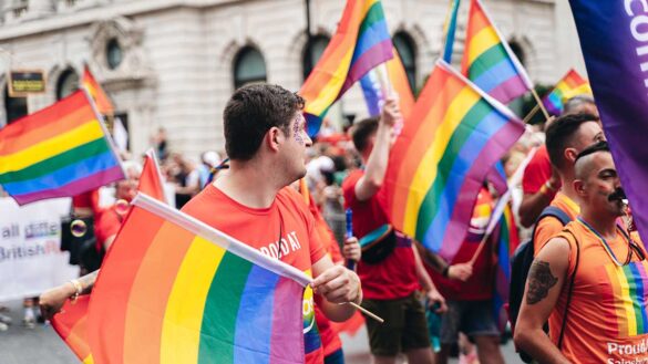 People marching during a Pride demonstration in London, waving LGBTQ+ Pride flags