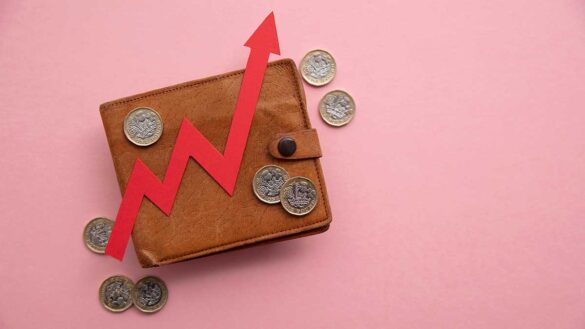 A wallet surrounded by pound coins, with a red upwards arrow on top of it