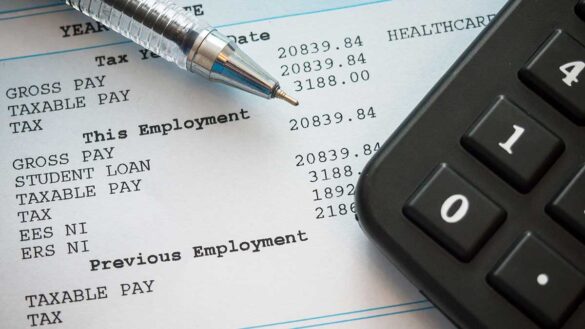 A close up of a payslip, with a calculator and a pen on top of it