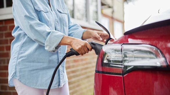A woman plugging an EV charger into an electric car at home