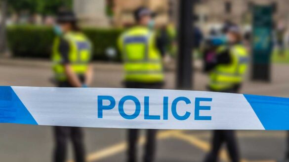 Police tape with officers in the background