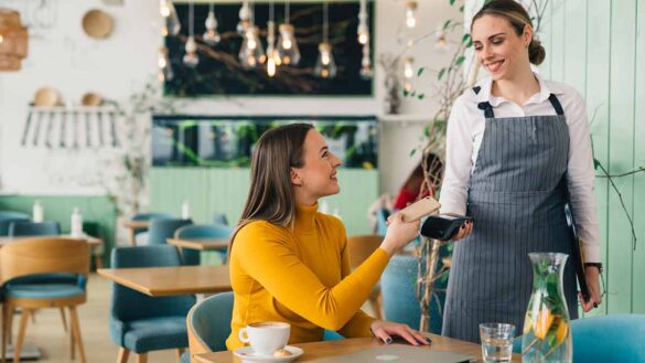 Tipping code of practice. Image shows a woman paying a bill in a restaurant.