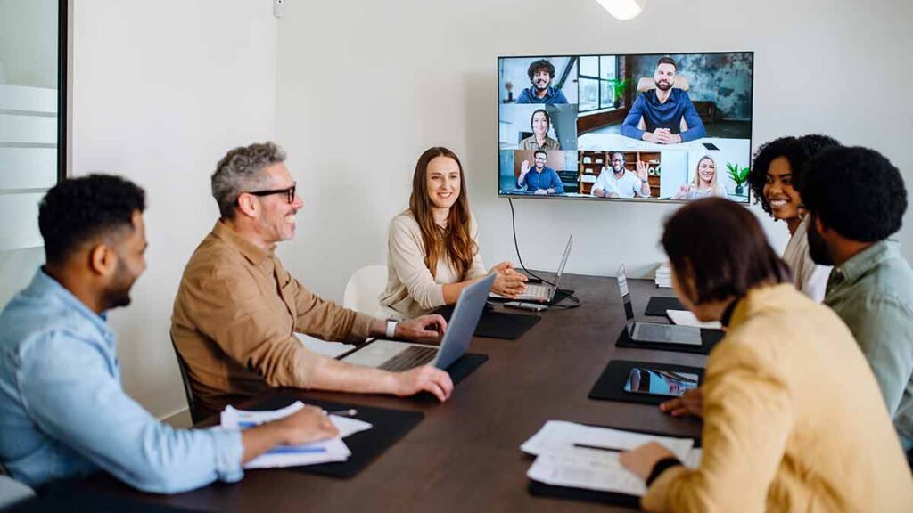 Optimising remote working: photo shows a meeting in an office with video conferencing