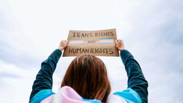 EHRC gender consultation extension. Photo shows a person holding a banner says "Trans rights are human rights"