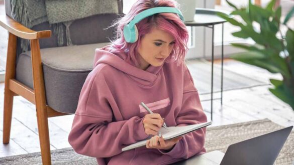 Gen Z in work situationships with employers: Photo shows young employee on a laptop with headphones.