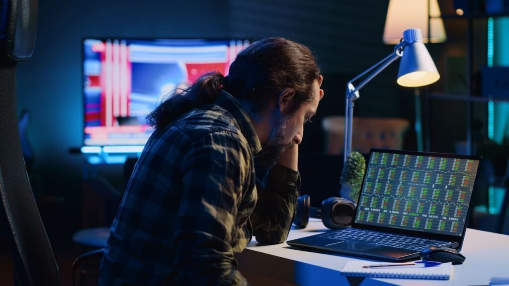 pony tailed man staring at laptop