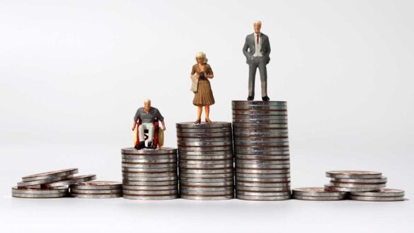 Disability and ethnicity pay gap reporting. Image shows small figures of a disabled man, a woman and a man in three increasingly tall stacks of coins.