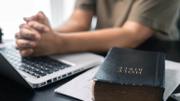 Federal employees encouraged to express religion in the workplace. Photo shows a man at a desk with a laptop and a Bible.