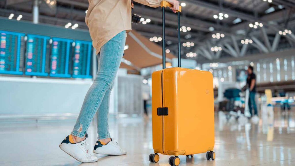 Young people wanting to emigrate from UK. Photo shows a young woman with a suitcase at an airport.