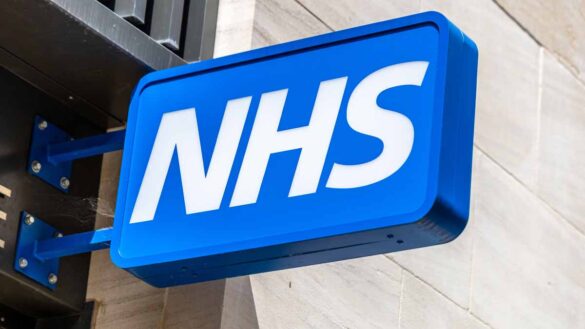 Nurse and midwife graduate guarantee. Photo shows an NHS sign.