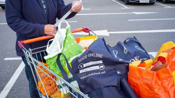 Inflation August 2025. Photo shows a woman reading a receipt in a supermarket car park.