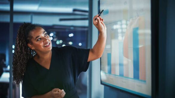 IoD Business Confidence, August 2025. Photo shows a woman pointing to graphs in a meeting.