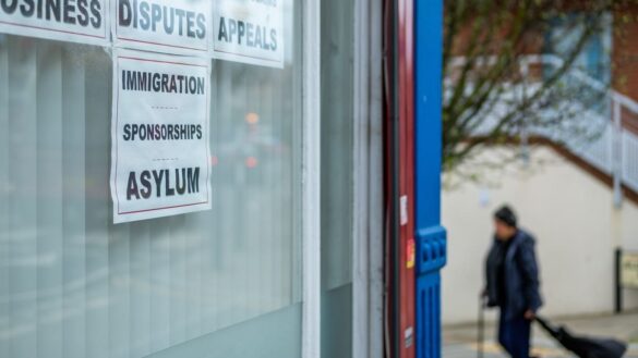 Immigration sponsorship sign on glass window, man in background