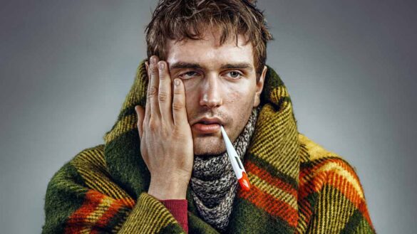 Sickness absence 2025 CIPD Simplyhealth: Photo shows poorly man with a blanket and a thermometer.